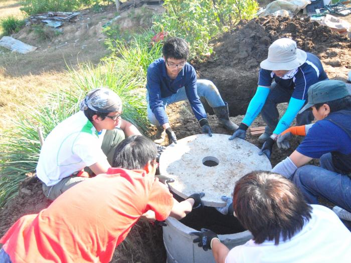 Student volunteers closing lid of the septic tank