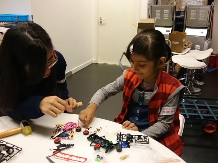 Volunteers teaching a kid to make a car