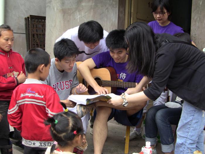 Volunteers playing guita and singing songs with the kids