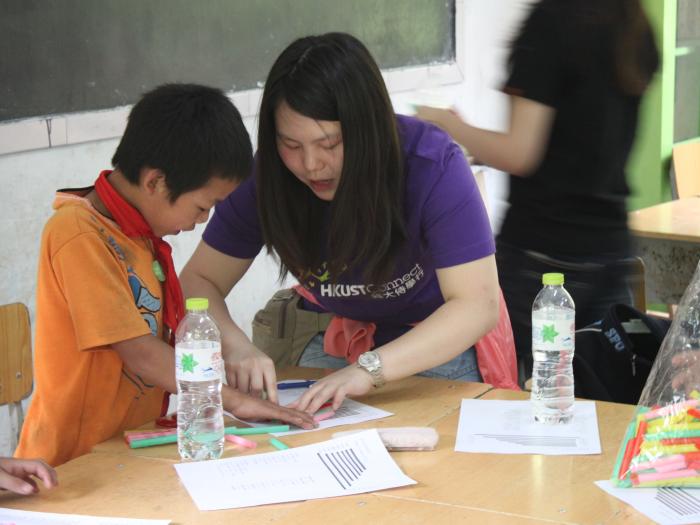 Volunteer helping the kid to make his own musical instrument