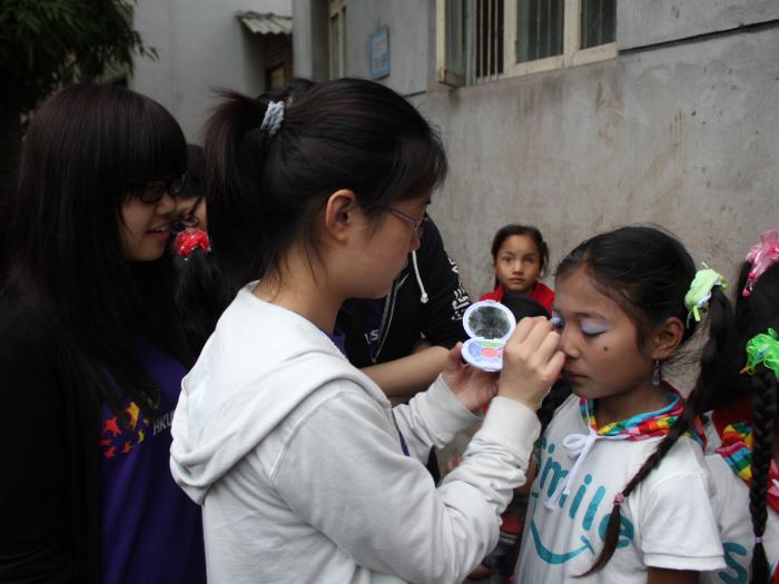 Volunteers helping childern to wear makeup for their performance