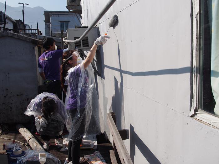 Volunteers painting the exterior wall of stilt house