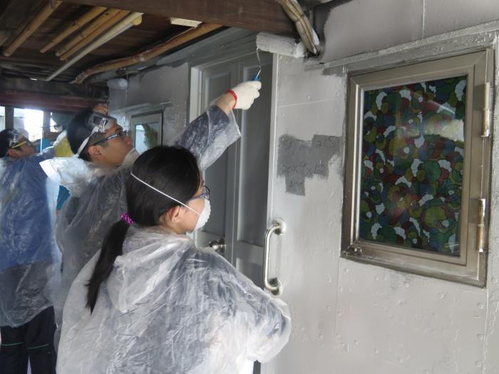 Volunteers painting the exterior wall of a stilt house