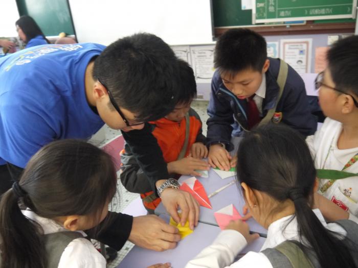 Volunteer assisting children with a paper-folding craft