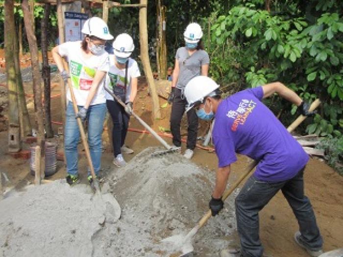 Volunteers engaging in physical labor to build a house for villagers