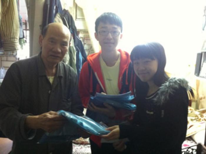 A pair of students visiting the elder with a gift