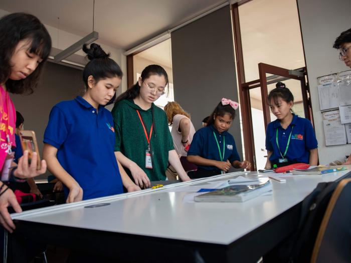 Volunteers demonstrating the theory of inclined planes by releasing a toy car on the table lifted up on one side