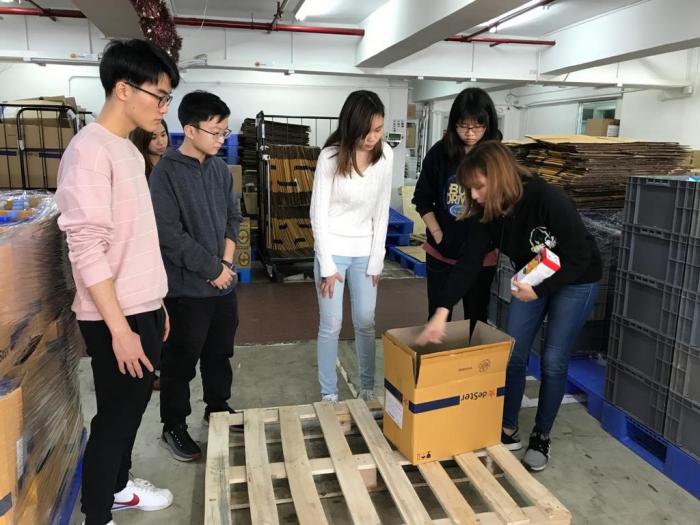 FHK staff took out two boxes and demonstrated the packing procedure with volunteers standing around her