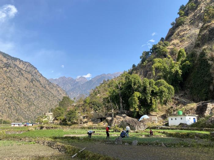 Students farmed in a farmland surrounded by mountains.