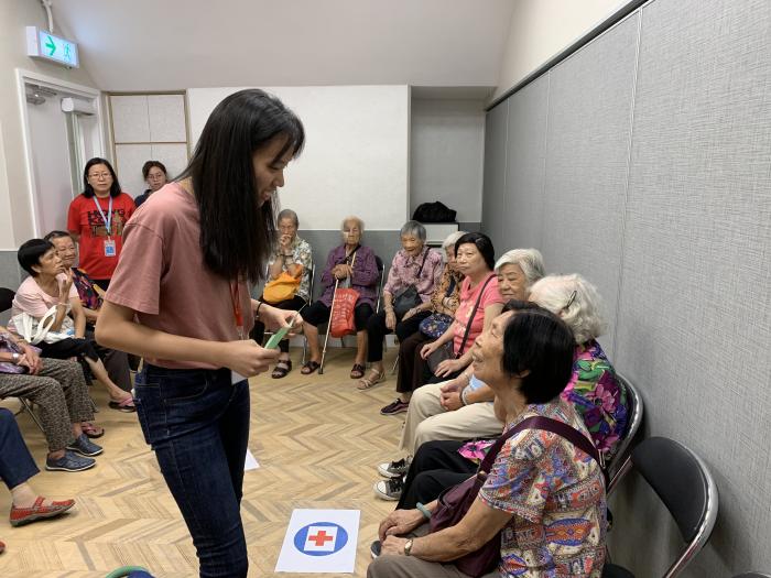 A volunteer is speaking to an elderly member during a game session