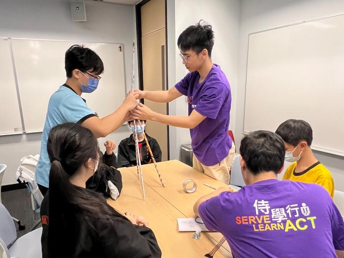 Volunteers building a paper tower with students