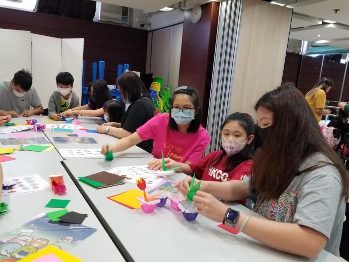 Volunteers teaching families to make an origami flower pot