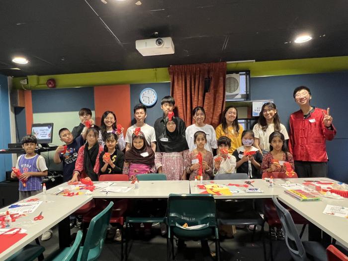 Volunteers taking pictures with the children holding up their paper dragons.