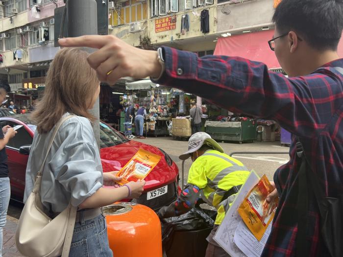 Students passing care package to street cleaners