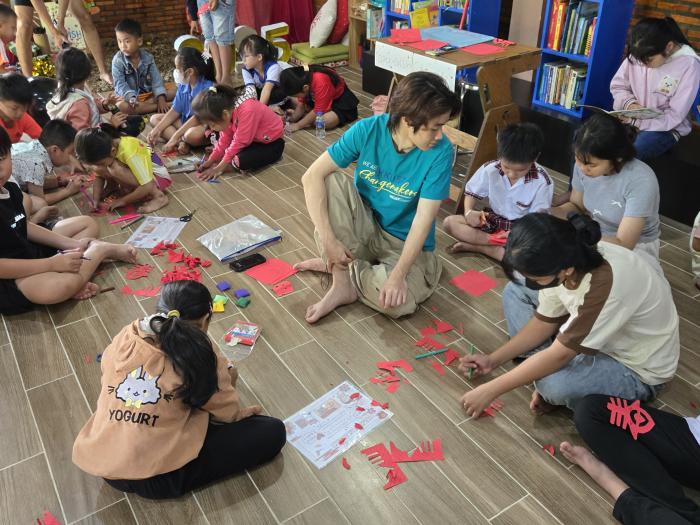 Volunteer teaching children traditional Chinese paper-cutting art in community carnival