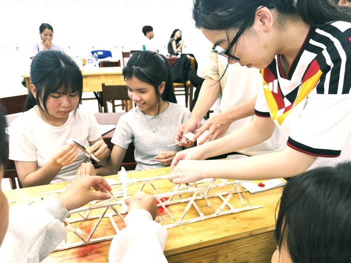 HKUST students facilitating in a STEM activity, guiding secondary school students to build wooden stick bridge
