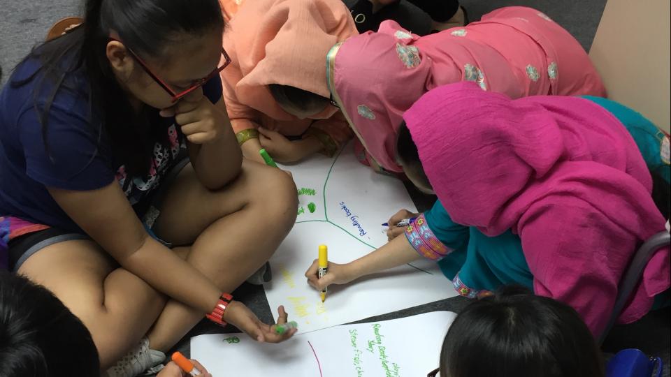 Volunteers and EM teenagers writing their ideas on a piece of paper together