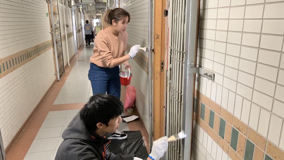 Volunteers painting metal gate of Moon Lok Dai Ha