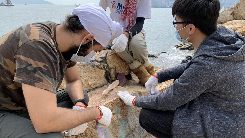Volunteers are cleaning the rock with sand paper