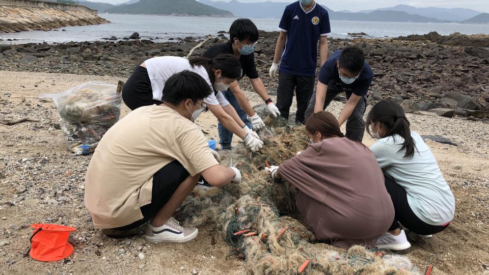Students cleaning the abandoned fishing net on the beach