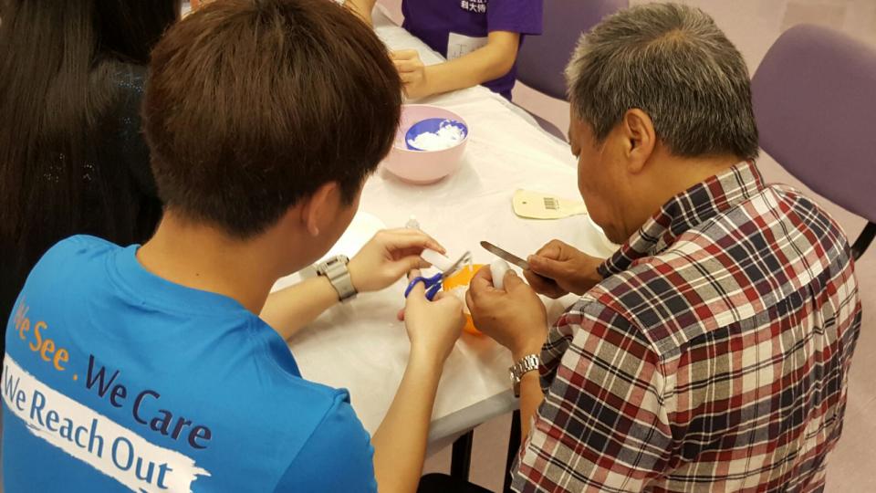 Volunteer assisting a visually impaired person with his artwork.  