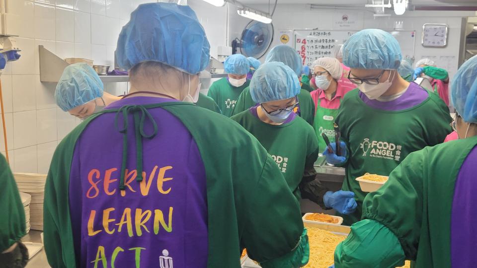 Volunteers in protective gear packing pasta into meal boxes