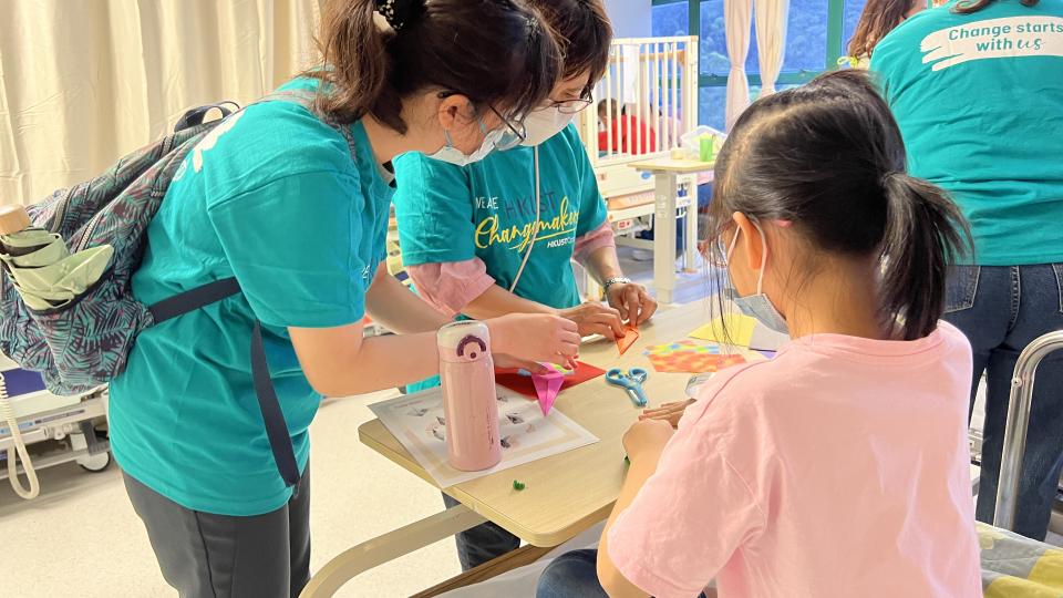 Volunteers making paper flower pots with a patient