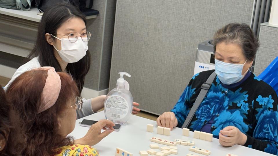 Students teaching elderly how to play Rummikub