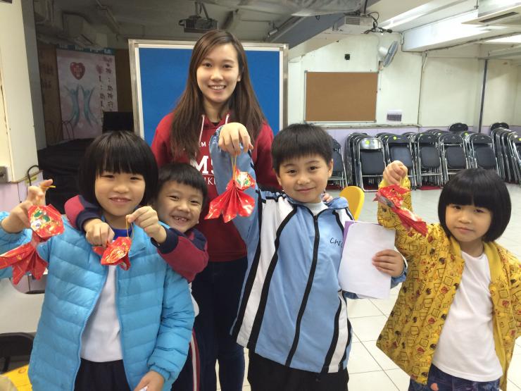Student leaders and children smiling happily with the Chinese New Year crafts in hand