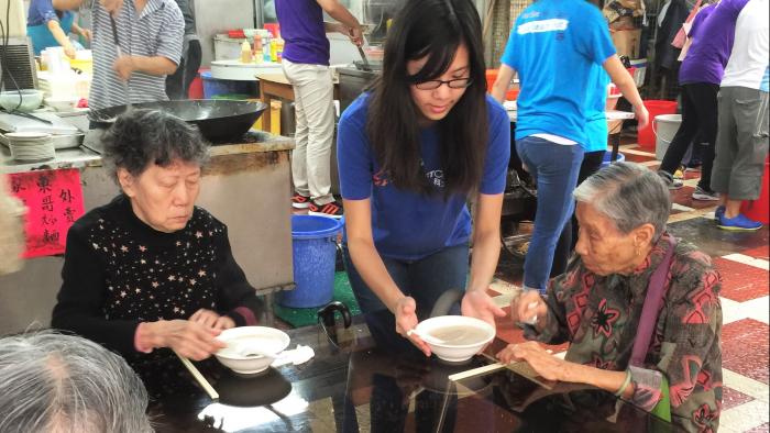 Volunteer helping in distribution of congee to the elders
