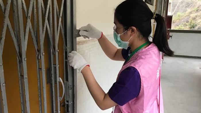 Volunteer removing rust from a gate