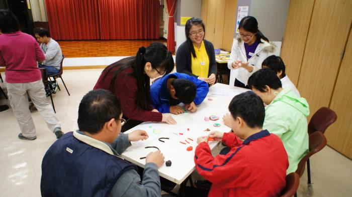 Volunteers teaching the service recipients to make craft using clay
