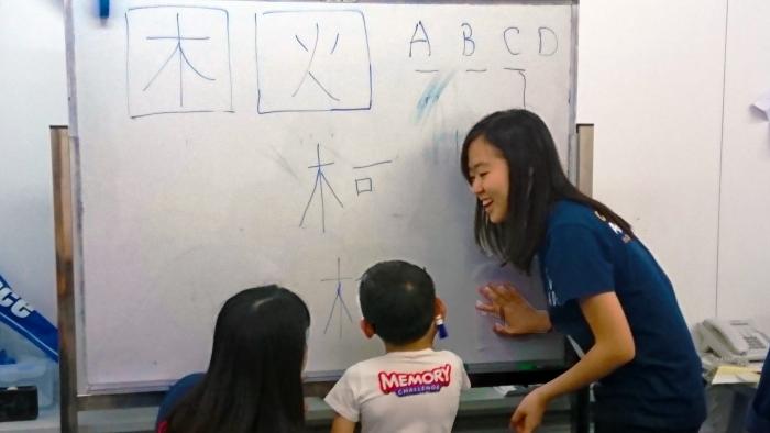 Volunteers teaching the children to write Chinese word