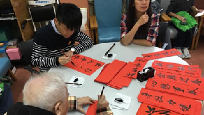 Volunteer writing fai chun with the elderly