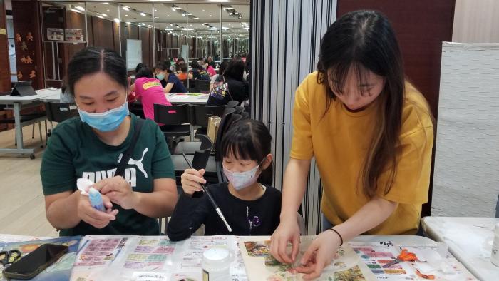 Volunteer guiding families on making a decoupage tote bag