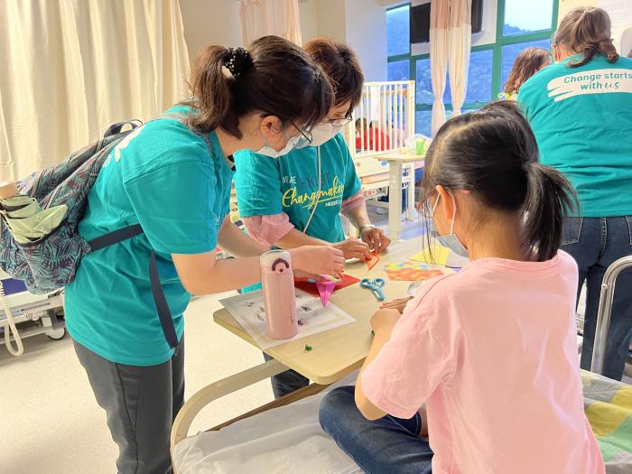 Volunteers making paper flower pots with a patient