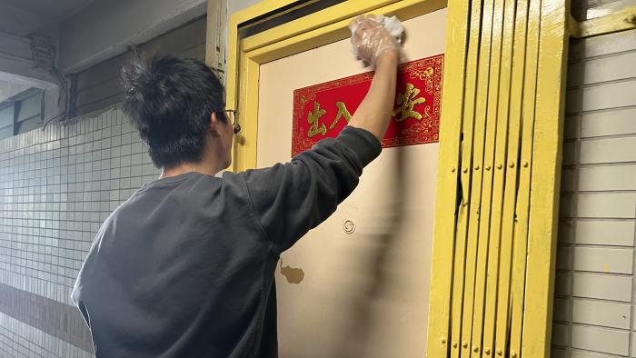 Volunteer cleaning the front gate for an elderly resident