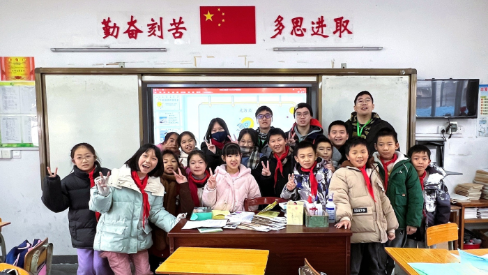 A classroom of smiles with volunteers and children.