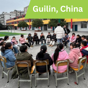volunteers and children sitting in a circle in playground